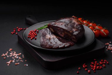 Lezzetli tütsülenmiş ya da kurutulmuş mahan atı eti sosisi baharat ve otlarla kaplı koyu beton arka planda.