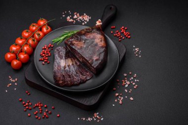 Lezzetli tütsülenmiş ya da kurutulmuş mahan atı eti sosisi baharat ve otlarla kaplı koyu beton arka planda.