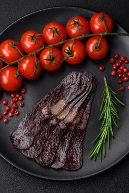 Lezzetli tütsülenmiş ya da kurutulmuş mahan atı eti sosisi baharat ve otlarla kaplı koyu beton arka planda.
