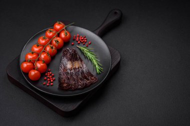 Lezzetli tütsülenmiş ya da kurutulmuş mahan atı eti sosisi baharat ve otlarla kaplı koyu beton arka planda.