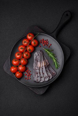 Lezzetli tütsülenmiş ya da kurutulmuş mahan atı eti sosisi baharat ve otlarla kaplı koyu beton arka planda.