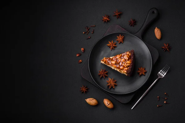 stock image Delicious fresh cheesecake cake or snickers with cream and nuts on a ceramic plate on a dark concrete background