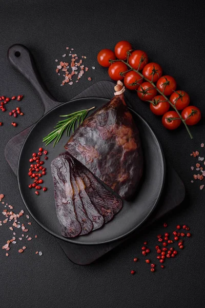 stock image Delicious smoked or cured mahan horse meat sausage with spices and herbs on a dark concrete background