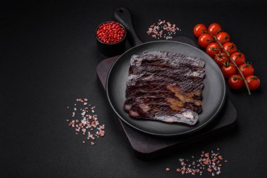 Lezzetli tütsülenmiş ya da kurutulmuş mahan atı eti sosisi baharat ve otlarla kaplı koyu beton arka planda.