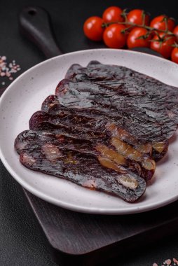 Lezzetli tütsülenmiş ya da kurutulmuş mahan atı eti sosisi baharat ve otlarla kaplı koyu beton arka planda.