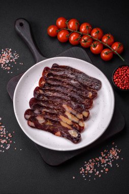 Lezzetli tütsülenmiş ya da kurutulmuş mahan atı eti sosisi baharat ve otlarla kaplı koyu beton arka planda.