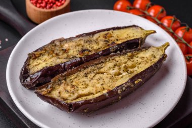 Tuz, baharat ve otlarla pişirilmiş, koyu beton arka planda iki parçaya ayrılmış lezzetli patlıcan.