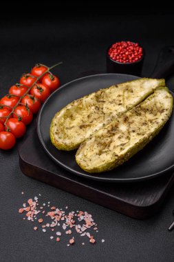 Tuz, baharat ve otlarla pişirilmiş, koyu beton arka planda iki parçaya bölünmüş lezzetli kabak.