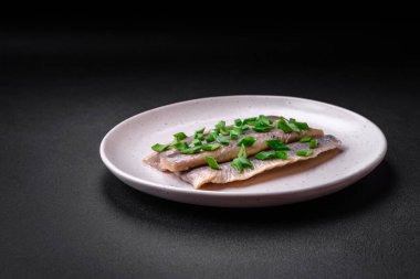 Lezzetli Atlantik ringa balığı koyu beton bir zeminde tuz ve baharatla marine edilmiş.