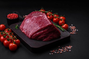 Tuzlu, baharatlı ve otlu taze çiğ et. Koyu beton bir arka planda tahta kesim tahtasının üzerinde.