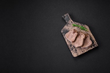 Lezzetli haşlanmış sığır dili. Koyu beton bir arka planda sebze ve baharatla dilimlenmiş.