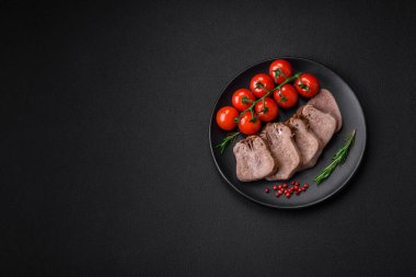 Lezzetli haşlanmış sığır dili. Koyu beton bir arka planda sebze ve baharatla dilimlenmiş.