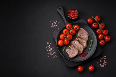 Lezzetli haşlanmış sığır dili. Koyu beton bir arka planda sebze ve baharatla dilimlenmiş.