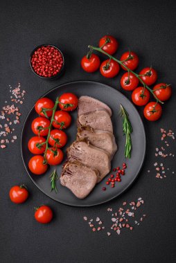 Lezzetli haşlanmış sığır dili. Koyu beton bir arka planda sebze ve baharatla dilimlenmiş.