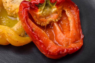 Lezzetli ızgara biber, baharat ve otlarla birlikte koyu beton bir arka planda.