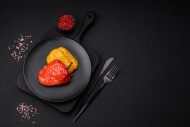 Lezzetli ızgara biber, baharat ve otlarla birlikte koyu beton bir arka planda.