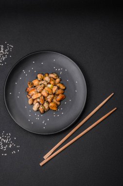 Çimento arka planında seramik tabakta baharat ve otlarla marine edilmiş lezzetli midyeler.