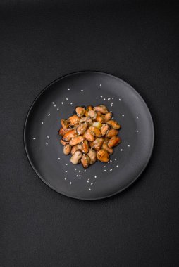 Çimento arka planında seramik tabakta baharat ve otlarla marine edilmiş lezzetli midyeler.