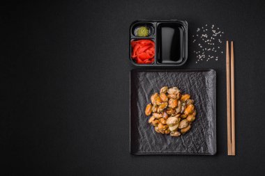 Çimento arka planında seramik tabakta baharat ve otlarla marine edilmiş lezzetli midyeler.