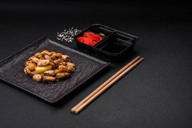 Çimento arka planında seramik tabakta baharat ve otlarla marine edilmiş lezzetli midyeler.