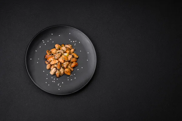 stock image Delicious marinated mussels with spices and herbs on a ceramic plate on a dark concrete background