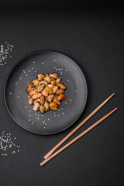 Çimento arka planında seramik tabakta baharat ve otlarla marine edilmiş lezzetli midyeler.