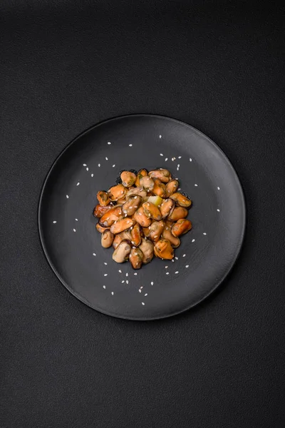 Çimento arka planında seramik tabakta baharat ve otlarla marine edilmiş lezzetli midyeler.