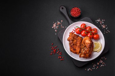 Lezzetli kızarmış levrek balığı. Koyu beton arka planda seramik bir tabakta baharat ve otlarla dilimler halinde.