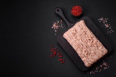 Ahşap kesme tahtasının üzerinde tuz, baharat ve otlarla kaplı taze doğranmış tavuk.