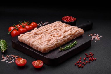 Ahşap kesme tahtasının üzerinde tuz, baharat ve otlarla kaplı taze doğranmış tavuk.