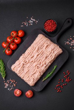 Ahşap kesme tahtasının üzerinde tuz, baharat ve otlarla kaplı taze doğranmış tavuk.