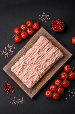 Ahşap kesme tahtasının üzerinde tuz, baharat ve otlarla kaplı taze doğranmış tavuk.