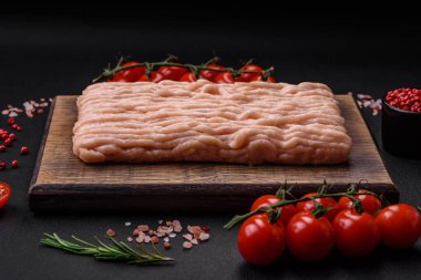 Ahşap kesme tahtasının üzerinde tuz, baharat ve otlarla kaplı taze doğranmış tavuk.