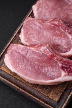 Kemikte çiğ domuz eti ya da tuz, baharat ve otlarla dilimlenmiş koyu beton arka planda kesilmiş kaburga.