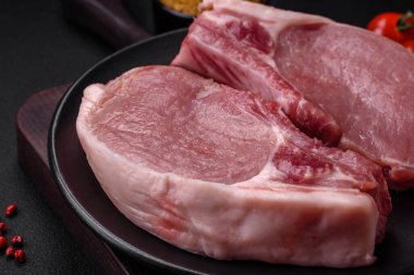 Kemikte çiğ domuz eti ya da tuz, baharat ve otlarla dilimlenmiş koyu beton arka planda kesilmiş kaburga.