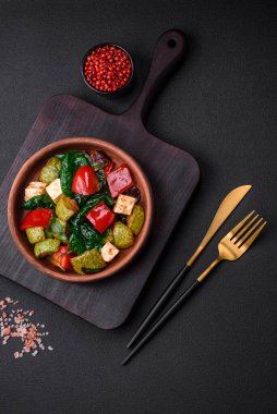 Lezzetli taze kabak salatası, peynir, tatlı biber, baharatlı ıspanak ve çimento kaplı seramik tabakta otlar.