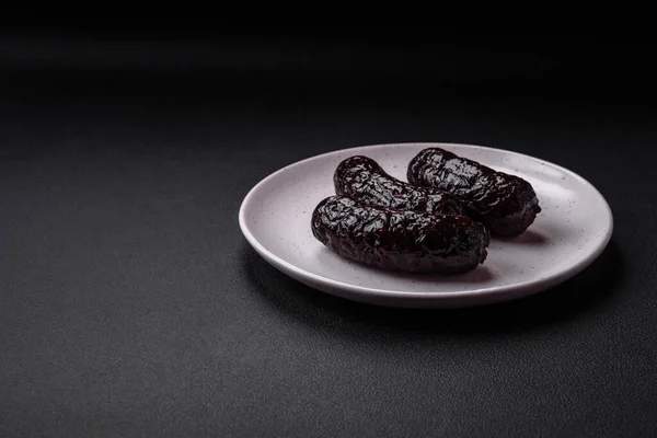 stock image Delicious black blood sausage or black pudding with spices and herbs grilled on a black concrete background