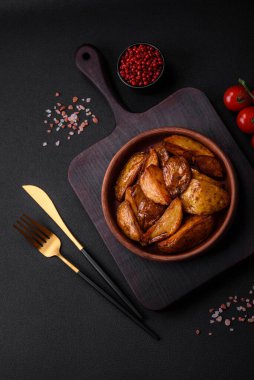 Lezzetli ızgara patates dilimleri, sarımsak, baharat ve otlar koyu beton arka planda.