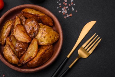 Lezzetli ızgara patates dilimleri, sarımsak, baharat ve otlar koyu beton arka planda.