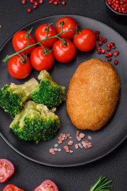 Lezzetli fırınlanmış pirzola, baharatlar, tuz ve otlarla kaplanmış koyu beton bir arka planda.