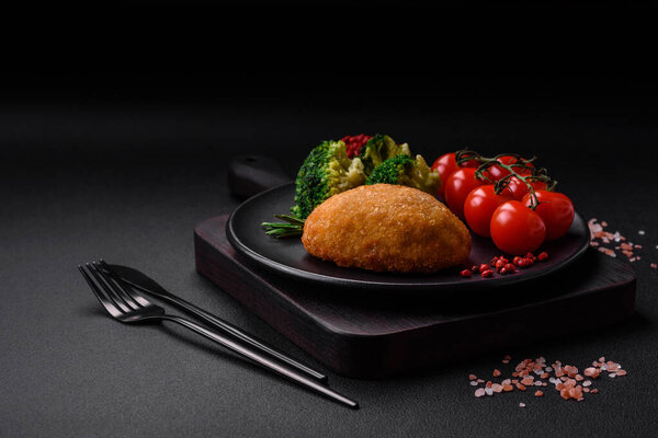 Delicious baked cutlet breaded with spices, salt and herbs on a dark concrete background