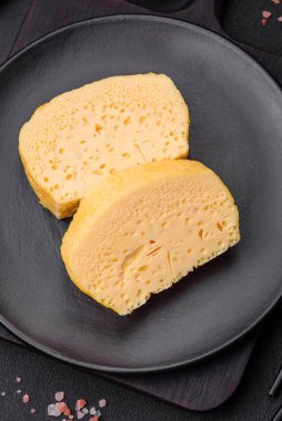 Sütlü, baharatlı ve otlu leziz omlet koyu beton arka planda seramik bir tabakta büyük parçalar halinde kesilmiş.