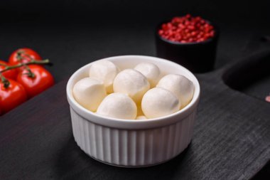 Lezzetli taze mozzarella peyniri. Koyu beton arka planda tuz ve baharat içeren küçük toplar şeklinde.