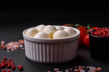 Lezzetli taze mozzarella peyniri. Koyu beton arka planda tuz ve baharat içeren küçük toplar şeklinde.