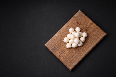 Lezzetli taze mozzarella peyniri. Koyu beton arka planda tuz ve baharat içeren küçük toplar şeklinde.