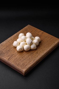 Lezzetli taze mozzarella peyniri. Koyu beton arka planda tuz ve baharat içeren küçük toplar şeklinde.