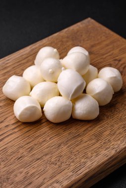 Lezzetli taze mozzarella peyniri. Koyu beton arka planda tuz ve baharat içeren küçük toplar şeklinde.