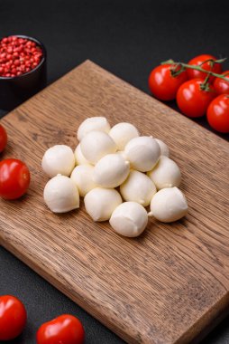 Lezzetli taze mozzarella peyniri. Koyu beton arka planda tuz ve baharat içeren küçük toplar şeklinde.