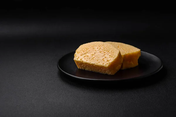 濃いコンクリートの背景にセラミックプレート上の大きな部分でカットおいしい多孔質黄色のチーズ — ストック写真
