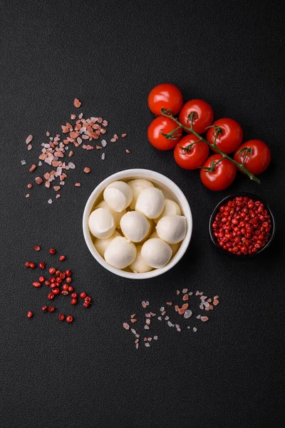 stock image Delicious fresh mozzarella cheese in the form of small balls with salt and spices on a dark concrete background